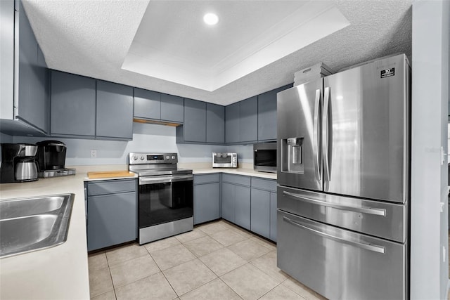 4076 Vana Dr, Sarasota, FL 34241 - kitchen with appliances with stainless steel finishes, a raised ceiling, light countertops, gray cabinets, and light tile patterned flooring