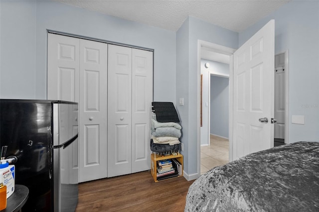 4076 Vana Dr, Sarasota, FL 34241 - bedroom featuring freestanding refrigerator, dark wood-style floors, a closet, a textured ceiling, and baseboards