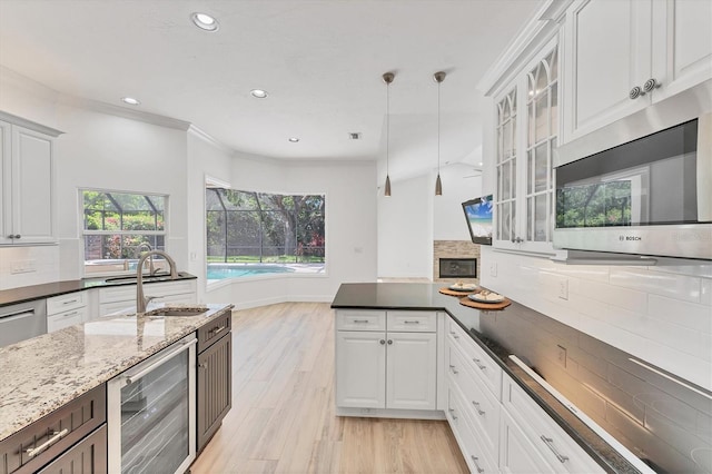 2914 Dick Wilson Dr, Sarasota, FL 34240 - kitchen with stainless steel microwave, a sink, decorative backsplash, white cabinetry, and crown molding