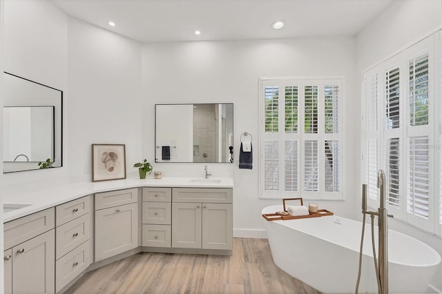 2914 Dick Wilson Dr, Sarasota, FL 34240 - bathroom featuring double vanity, a freestanding bath, wood finished floors, and recessed lighting