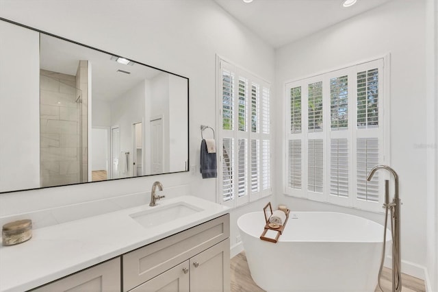 2914 Dick Wilson Dr, Sarasota, FL 34240 - full bath featuring a freestanding tub, vanity, wood finished floors, baseboards, and recessed lighting