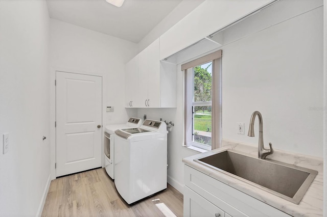 2914 Dick Wilson Dr, Sarasota, FL 34240 - laundry room featuring washer and clothes dryer, cabinet space, light wood finished floors, and baseboards