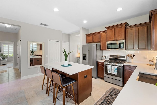 12327 Halfmoon Lake Ter, Bradenton, FL 34211 - kitchen featuring stainless steel appliances, light countertops, a kitchen bar, a kitchen island, and backsplash