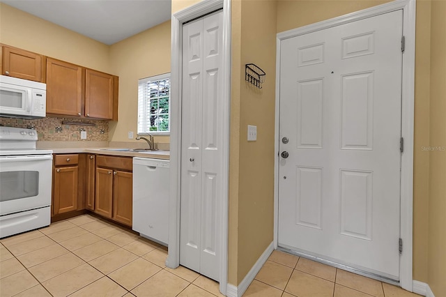 3707 45th Ter W Unit 104, Bradenton, FL 34210 - kitchen with white appliances, light tile patterned floors, a sink, and brown cabinetry