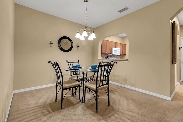 3707 45th Ter W Unit 104, Bradenton, FL 34210 - dining space with arched walkways, light colored carpet, baseboards, and a chandelier