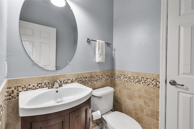 3707 45th Ter W Unit 104, Bradenton, FL 34210 - bathroom with tile walls, toilet, vanity, and a wainscoted wall