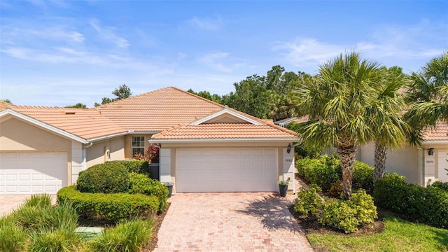 5866 Guarino Dr, Sarasota, FL 34238 - view of front of home with stucco siding, a tile roof, decorative driveway, and an attached garage