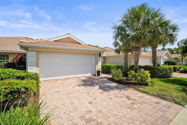 5866 Guarino Dr, Sarasota, FL 34238 - view of front of property featuring stucco siding, decorative driveway, a tiled roof, and a garage