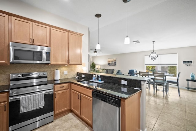 5866 Guarino Dr, Sarasota, FL 34238 - kitchen with appliances with stainless steel finishes, a sink, a peninsula, decorative backsplash, and dark stone countertops