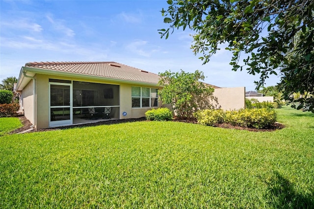5866 Guarino Dr, Sarasota, FL 34238 - rear view of house featuring stucco siding, a lawn, a tiled roof, and a sunroom