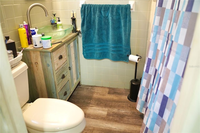 1099 6th Ave NE, Largo, FL 33770 - bathroom with tile walls, toilet, wood finished floors, a sink, and a shower with curtain