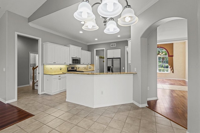 8930 Bloomfield Blvd, Sarasota, FL 34238 - kitchen with stainless steel appliances, arched walkways, a chandelier, light stone counters, and light tile patterned floors