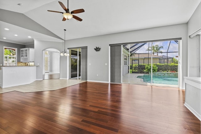 8930 Bloomfield Blvd, Sarasota, FL 34238 - unfurnished living room featuring a ceiling fan, hardwood / wood-style flooring, a chandelier, lofted ceiling, and arched walkways