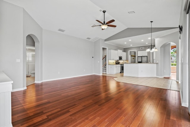 8930 Bloomfield Blvd, Sarasota, FL 34238 - unfurnished living room featuring arched walkways, a ceiling fan, light wood-type flooring, lofted ceiling, and stairs