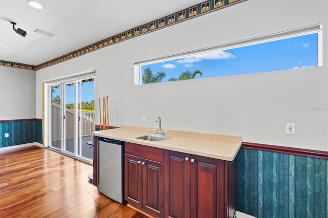 8930 Bloomfield Blvd, Sarasota, FL 34238 - kitchen featuring dishwasher, wainscoting, light wood-style flooring, light countertops, and reddish brown cabinets