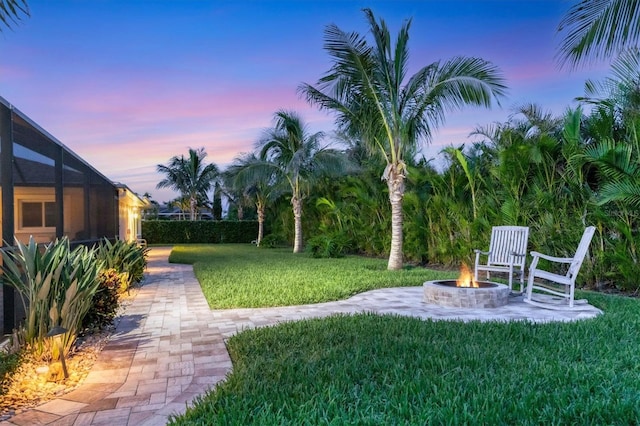 7913 19th Avenue Dr W, Bradenton, FL 34209 - yard at dusk featuring a yard, an outdoor fire pit, a patio area, and glass enclosure