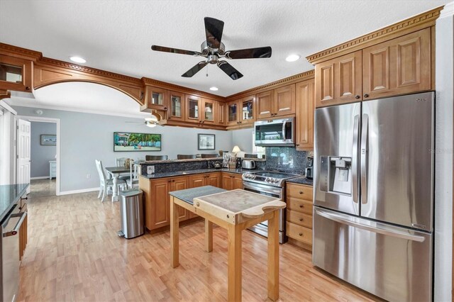 7913 19th Avenue Dr W, Bradenton, FL 34209 - kitchen featuring stainless steel appliances, a ceiling fan, a peninsula, brown cabinetry, and glass insert cabinets