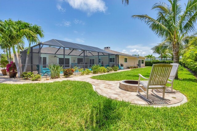 7913 19th Avenue Dr W, Bradenton, FL 34209 - rear view of house with a fire pit, a lawn, a ceiling fan, a patio area, and glass enclosure