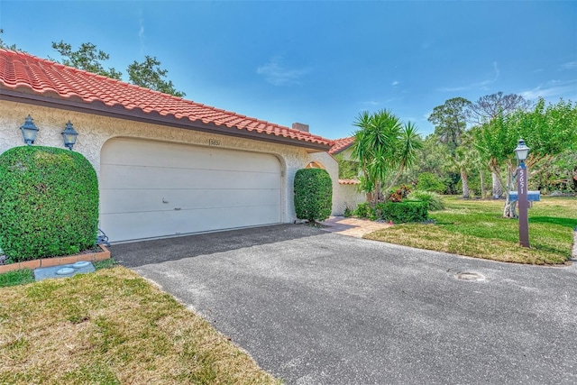5651 Golf Pointe Dr Unit 5651, Sarasota, FL 34243 - mediterranean / spanish-style house featuring driveway, stucco siding, a tiled roof, a garage, and a front lawn