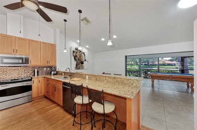 5651 Golf Pointe Dr Unit 5651, Sarasota, FL 34243 - kitchen featuring stainless steel appliances, a sink, a peninsula, backsplash, and light stone countertops