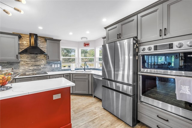 12714 Tyler Run Ave, Odessa, FL 33556 - kitchen featuring wall chimney range hood, appliances with stainless steel finishes, a sink, gray cabinets, and light wood finished floors