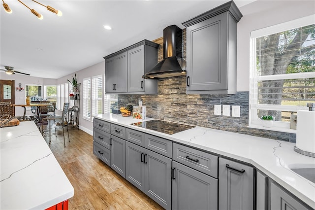 12714 Tyler Run Ave, Odessa, FL 33556 - kitchen with wall chimney range hood, gray cabinets, black electric stovetop, backsplash, and ceiling fan