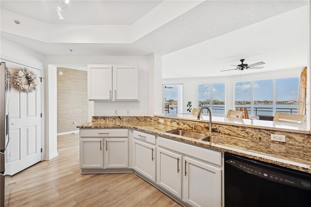 516 Tamiami Trl S Unit 306, Nokomis, FL 34275 - kitchen with black dishwasher, a sink, light stone counters, light wood-style flooring, and a ceiling fan