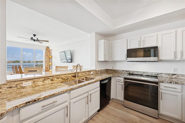 516 Tamiami Trl S Unit 306, Nokomis, FL 34275 - kitchen with stainless steel appliances, a sink, light wood finished floors, white cabinetry, and light stone countertops