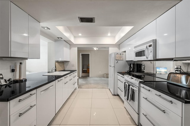 139 Adair Ave, Sarasota, FL 34243 - kitchen with white appliances, a sink, a raised ceiling, white cabinets, and dark countertops