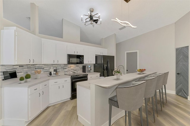 5742 39th Street Cir E, Bradenton, FL 34203 - kitchen featuring black appliances, a chandelier, light wood finished floors, decorative backsplash, and white cabinets