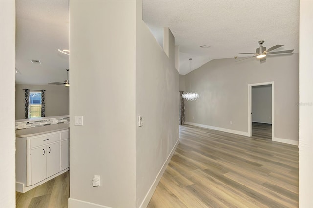 5742 39th Street Cir E, Bradenton, FL 34203 - hallway featuring light wood-style flooring, baseboards, lofted ceiling, and a textured ceiling
