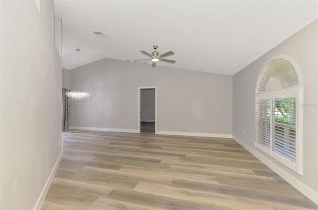 5742 39th Street Cir E, Bradenton, FL 34203 - unfurnished living room with a ceiling fan, a chandelier, vaulted ceiling, light wood-type flooring, and baseboards