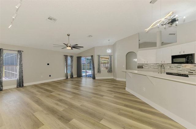 5742 39th Street Cir E, Bradenton, FL 34203 - unfurnished living room with a ceiling fan, vaulted ceiling, light wood-style floors, baseboards, and rail lighting