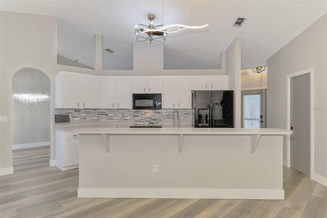 5742 39th Street Cir E, Bradenton, FL 34203 - kitchen featuring black appliances, a chandelier, tasteful backsplash, white cabinetry, and high vaulted ceiling