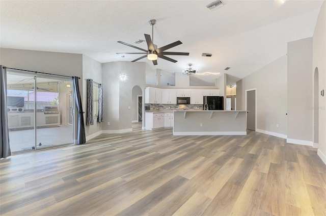 5742 39th Street Cir E, Bradenton, FL 34203 - unfurnished living room featuring arched walkways, vaulted ceiling, ceiling fan, baseboards, and light wood-style flooring