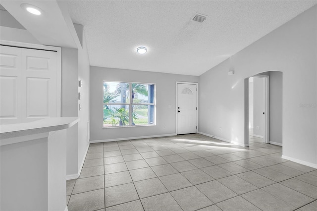 1062 Blossom Dr, Sebastian, FL 32958 - foyer entrance with arched walkways, light tile patterned floors, a textured ceiling, baseboards, and lofted ceiling