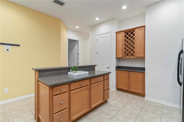 7314 Hamilton Rd, Bradenton, FL 34209 - kitchen featuring dark countertops, light tile patterned floors, a kitchen island, recessed lighting, and brown cabinetry