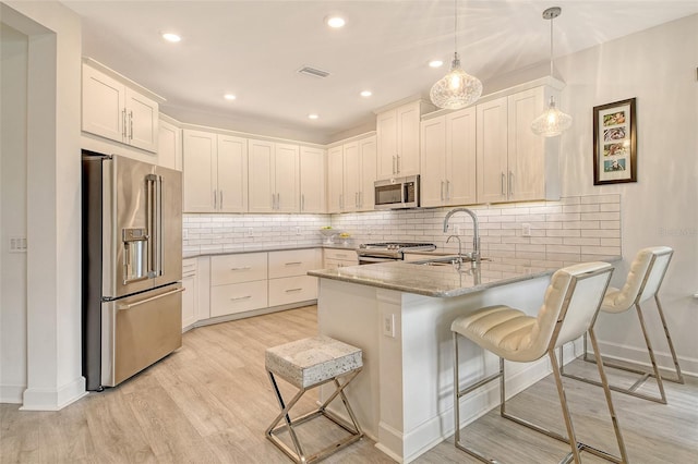 5475 Summit Gln, Bradenton, FL 34203 - kitchen with appliances with stainless steel finishes, a sink, a peninsula, light stone countertops, and light wood-style floors