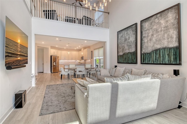 5475 Summit Gln, Bradenton, FL 34203 - living room with light wood-type flooring, a chandelier, a high ceiling, and baseboards