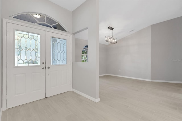 4473 Diamond Cir S, Sarasota, FL 34233 - foyer entrance with a chandelier, baseboards, lofted ceiling, and light wood finished floors