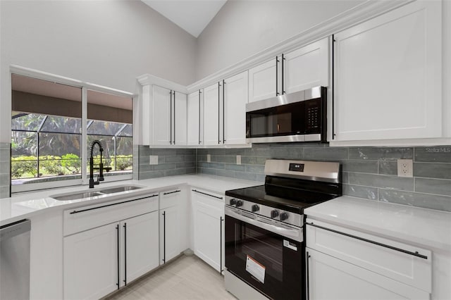 4473 Diamond Cir S, Sarasota, FL 34233 - kitchen featuring appliances with stainless steel finishes, a sink, tasteful backsplash, white cabinetry, and vaulted ceiling