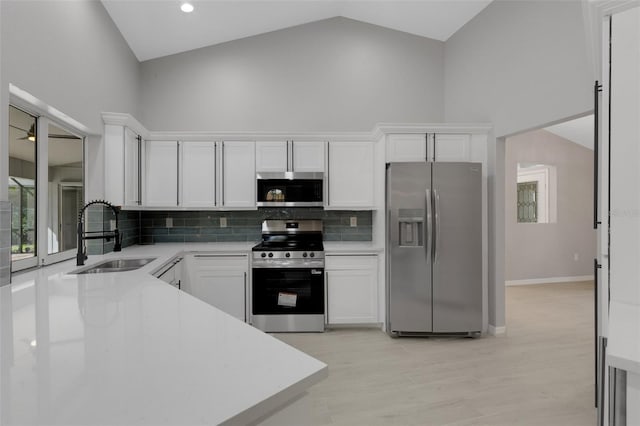 4473 Diamond Cir S, Sarasota, FL 34233 - kitchen with appliances with stainless steel finishes, a sink, tasteful backsplash, white cabinetry, and high vaulted ceiling