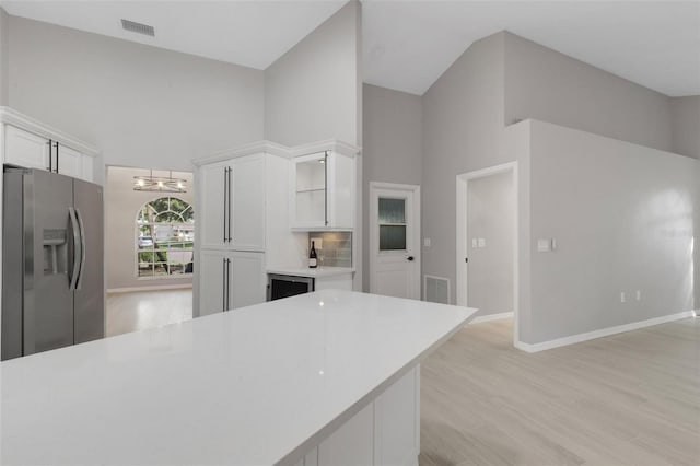 4473 Diamond Cir S, Sarasota, FL 34233 - kitchen with stainless steel fridge, high vaulted ceiling, white cabinetry, light countertops, and a chandelier