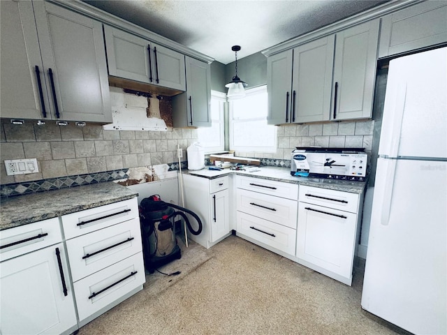 104 Pops Ln, Nokomis, FL 34275 - kitchen with freestanding refrigerator, decorative backsplash, gray cabinetry, decorative light fixtures, and dark countertops