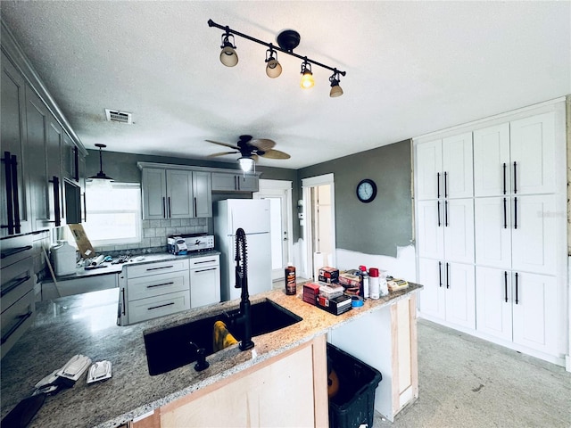 104 Pops Ln, Nokomis, FL 34275 - kitchen featuring a sink, a peninsula, freestanding refrigerator, light stone counters, and pendant lighting
