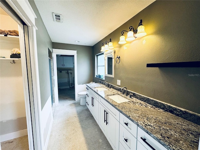 104 Pops Ln, Nokomis, FL 34275 - bathroom featuring toilet, double vanity, a textured ceiling, a spacious closet, and baseboards