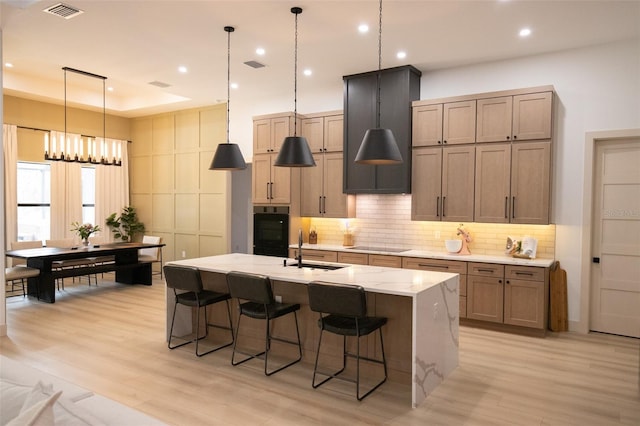 6713 Taneytown St, North Port, FL 34291 - kitchen with light wood-type flooring, a sink, tasteful backsplash, a kitchen island with sink, and a kitchen breakfast bar