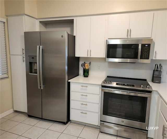 2124 N Tamiami Trl Unit 108, Sarasota, FL 34234 - kitchen with appliances with stainless steel finishes, light countertops, white cabinets, and light tile patterned flooring