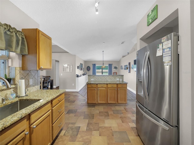 27 Sea Shark Path, Palm Coast, FL 32164 - kitchen with stainless steel refrigerator with ice dispenser, tasteful backsplash, baseboards, a sink, and light stone finish floors