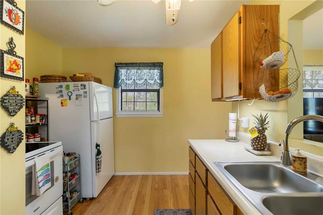 5403 Fleming St, Port Charlotte, FL 33981 - kitchen featuring white appliances, a sink, light wood-style flooring, light countertops, and brown cabinets